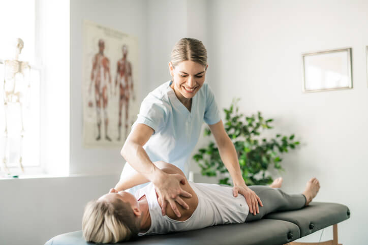 A female home support worker helping a recovering patient with light exercises