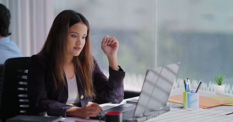 A focused female executive administrative assistant working on a laptop in an office