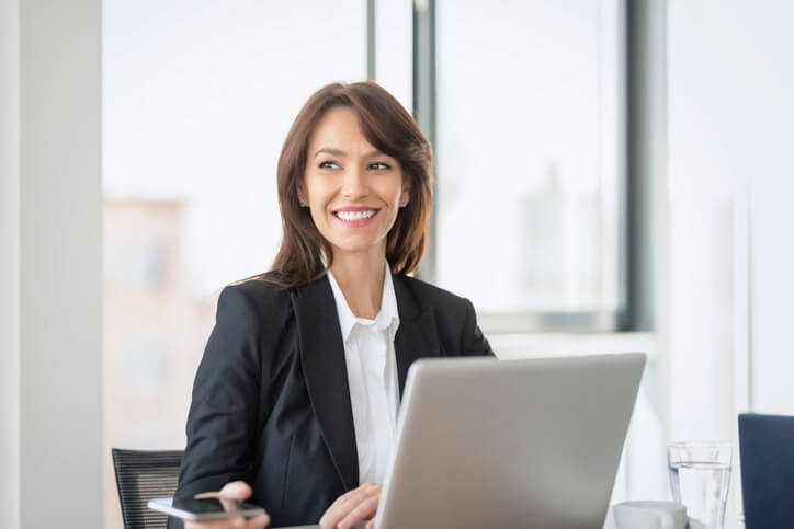 A cheerful executive administrative assistant sitting in an office at work