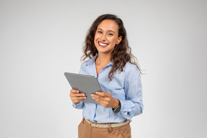 A smiling female entrepreneur holding a tablet after completing her business administration training