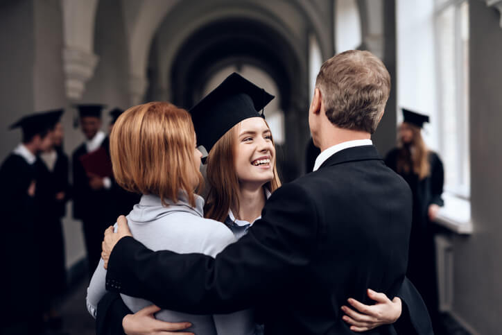 A happy female career college graduate with parents