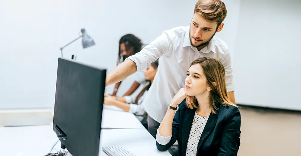 An employee receiving on-the-job training from a manager in a workplace setting.